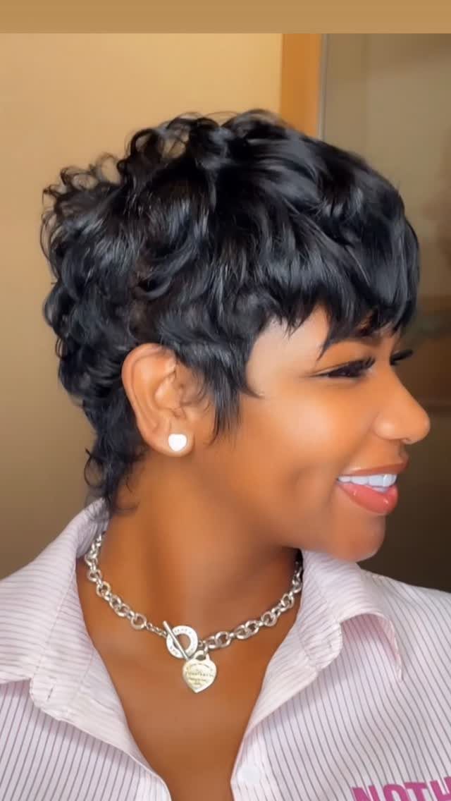 Woman with curly black pixie cut and short bangs smiling in profile view