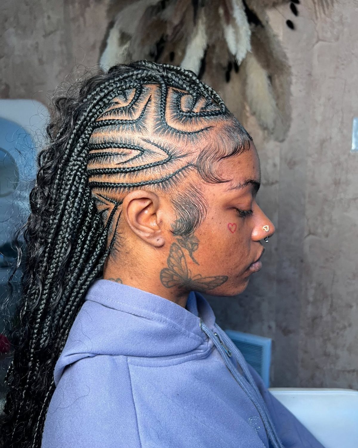 Person with intricate geometric cornrow braids styled into a braided faux hawk hairstyle.