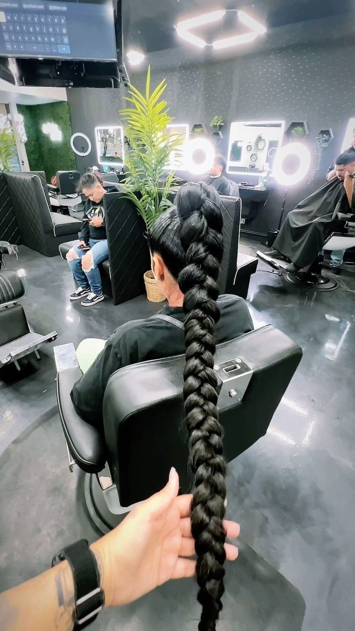 Long thick black braided ponytail on a person sitting in a salon chair.