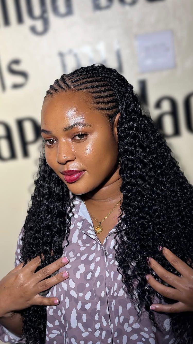 Woman with scalp cornrows and long loose afro curls in a half-up style.
