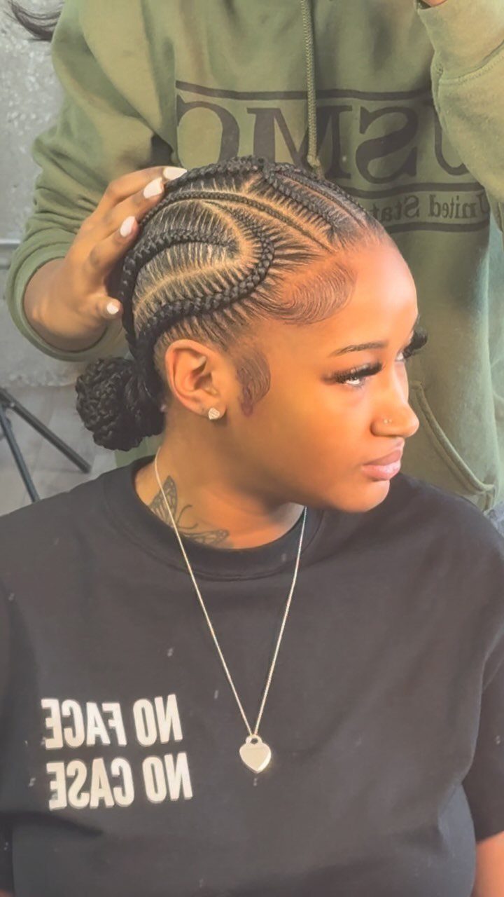 Woman with criss-cross cornrow braids styled into a low bun.