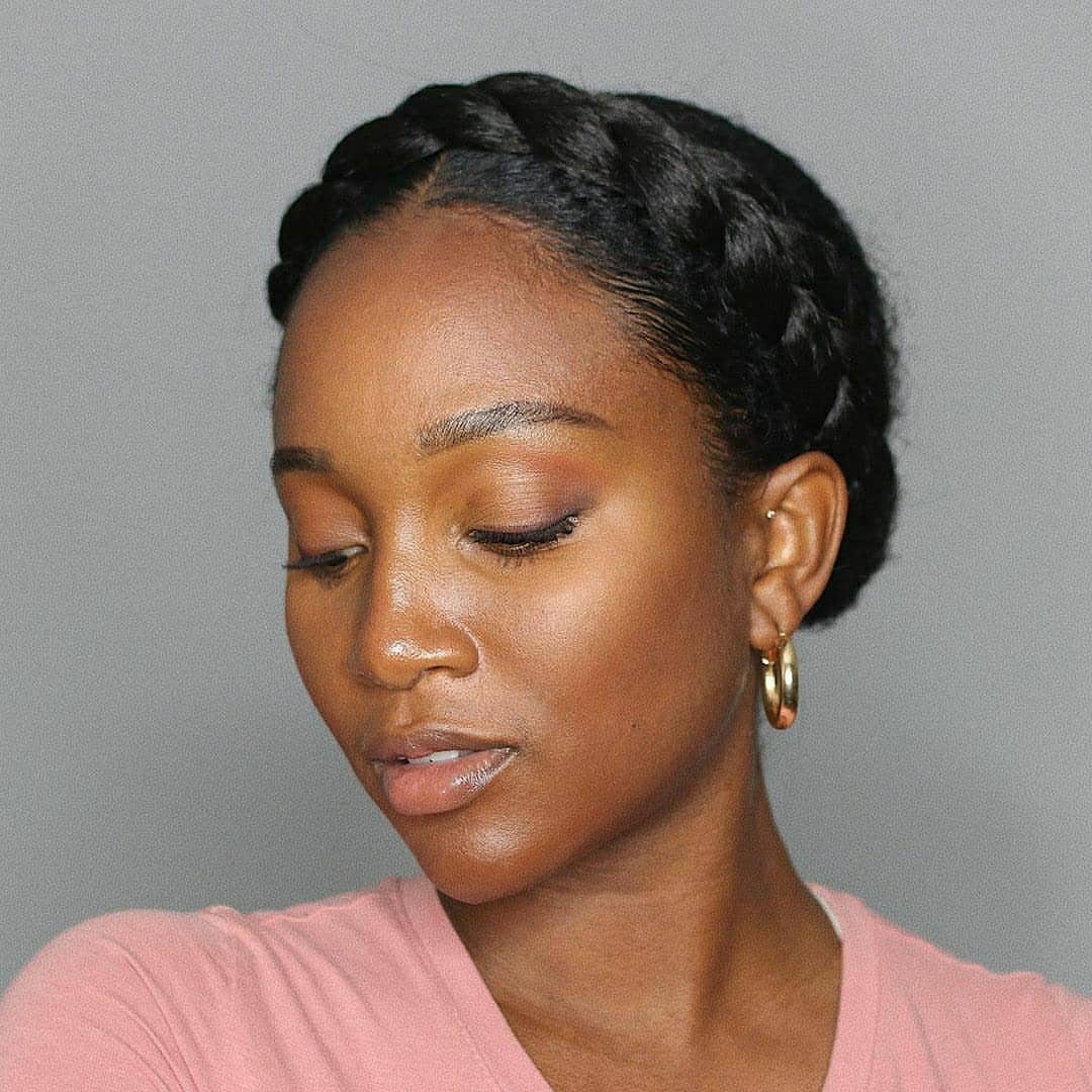 Woman with a thick dark crown braid circling her head and gold hoop earrings.