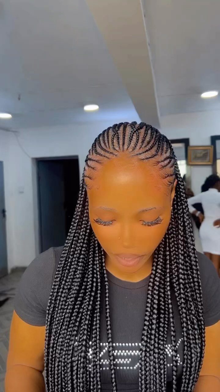 Woman with black Ghana braids cornrowed to the scalp and long hanging braids.