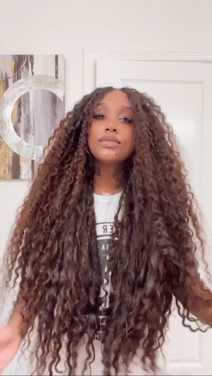 Woman with long brown goddess locs featuring curly ends and a white t-shirt.