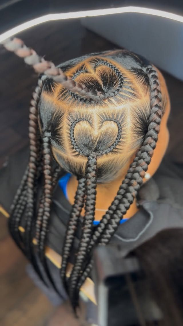 Black hair styled in cornrows with two heart-shaped patterns braided into the scalp.