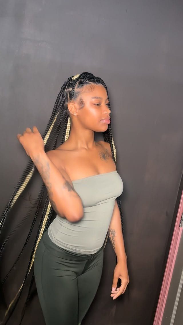 Woman with long black and blonde knotless braids wearing a green outfit.