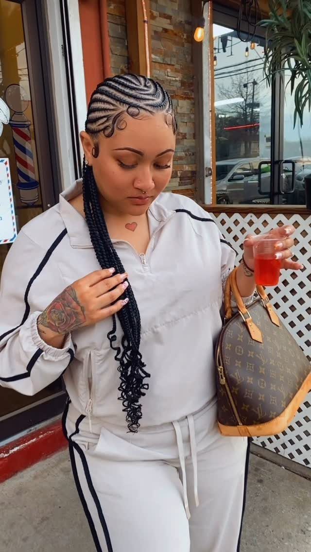 Woman with straight-back cornrows and curly ends wearing a white tracksuit and holding a handbag.
