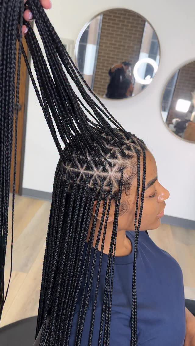 Person with long black box braids featuring distinct triangle-shaped parting on the scalp.