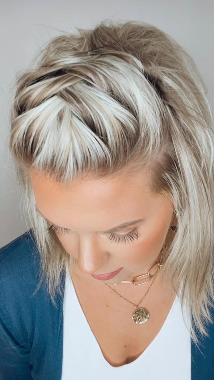 Woman with blonde hair featuring a braided crown hairstyle and gold jewelry.