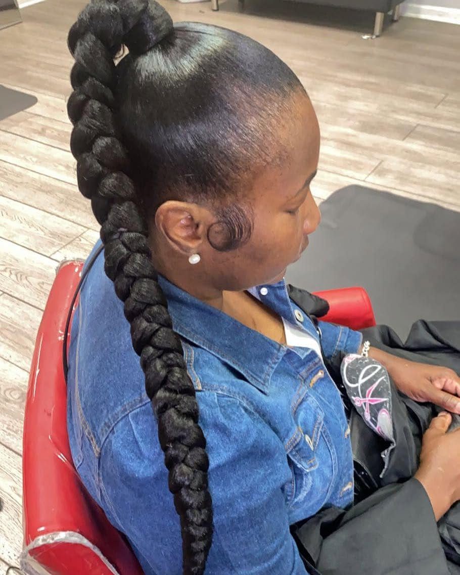 Woman with a high, thick braided ponytail and a blue denim shirt.