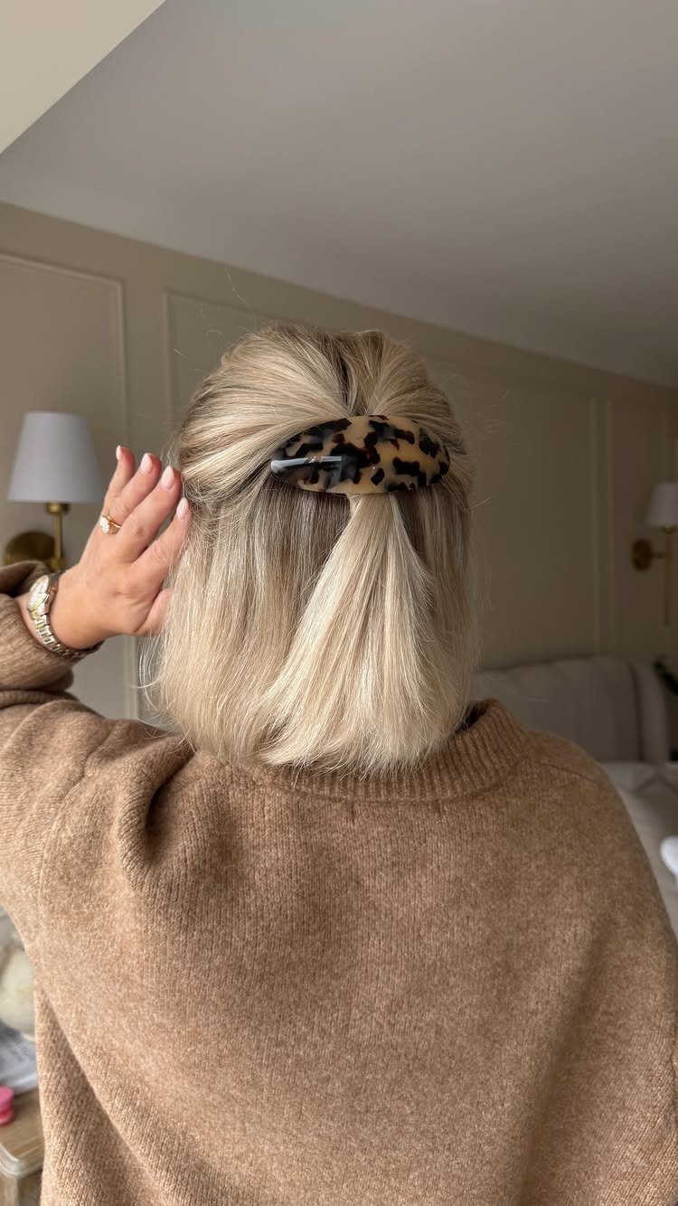 Blonde hair gathered in a half-up style secured with a leopard print clip.