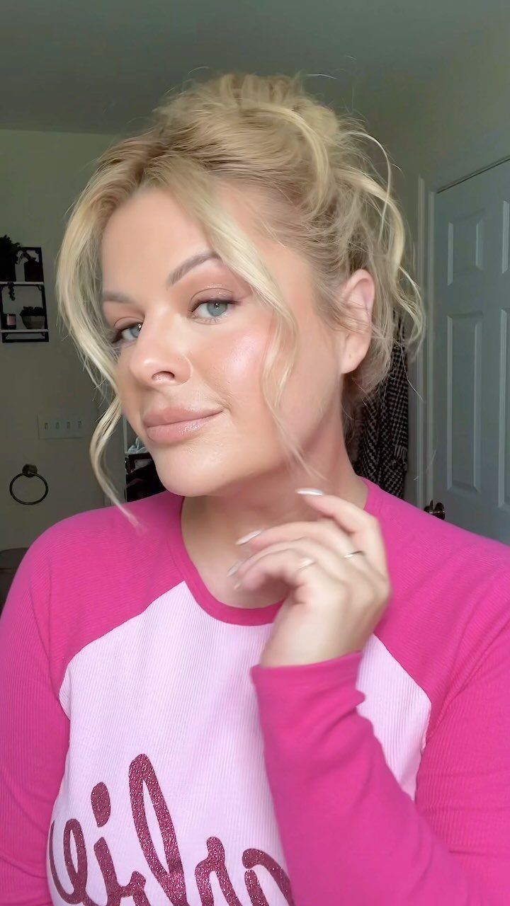 Woman with blonde hair styled in a relaxed messy bun and loose strands.