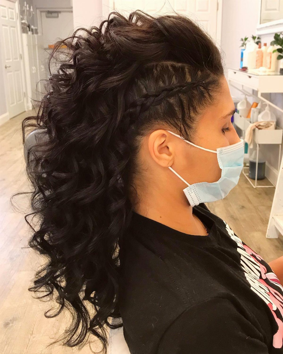 Woman with dark curly hair styled in a textured faux hawk with side braid.