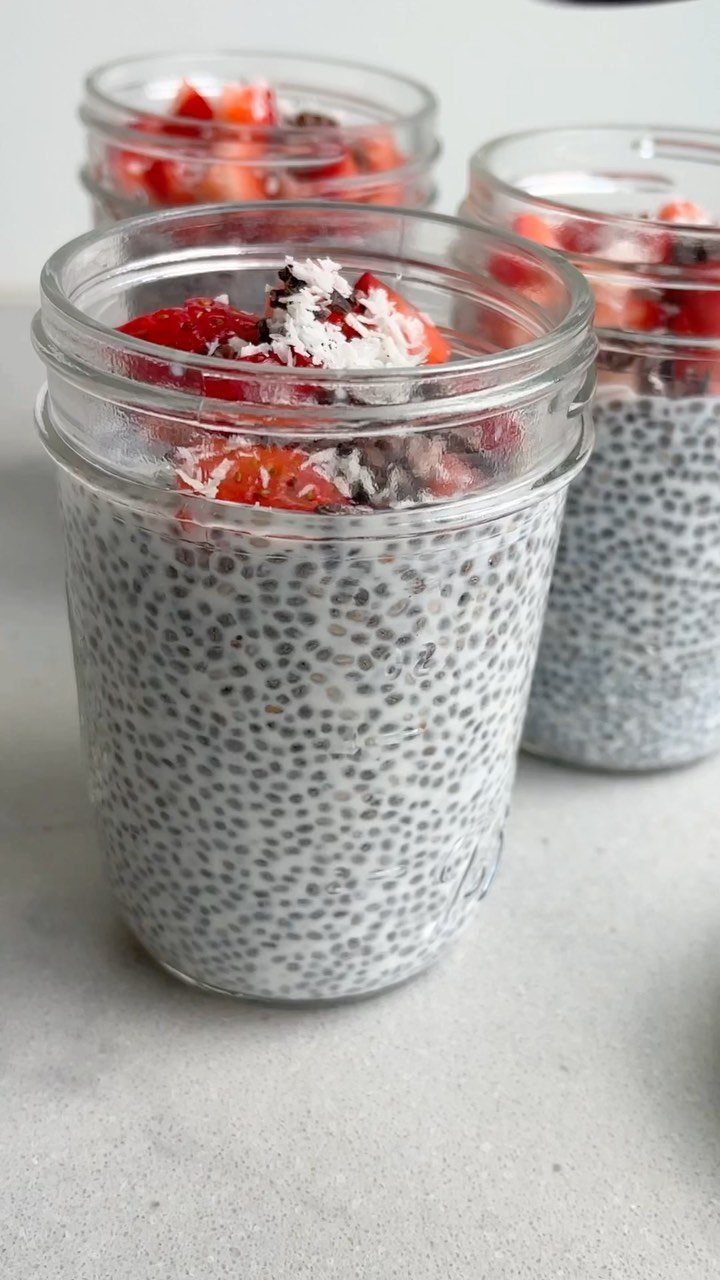 Chia seed pudding in glass jars topped with fresh strawberries and coconut flakes.