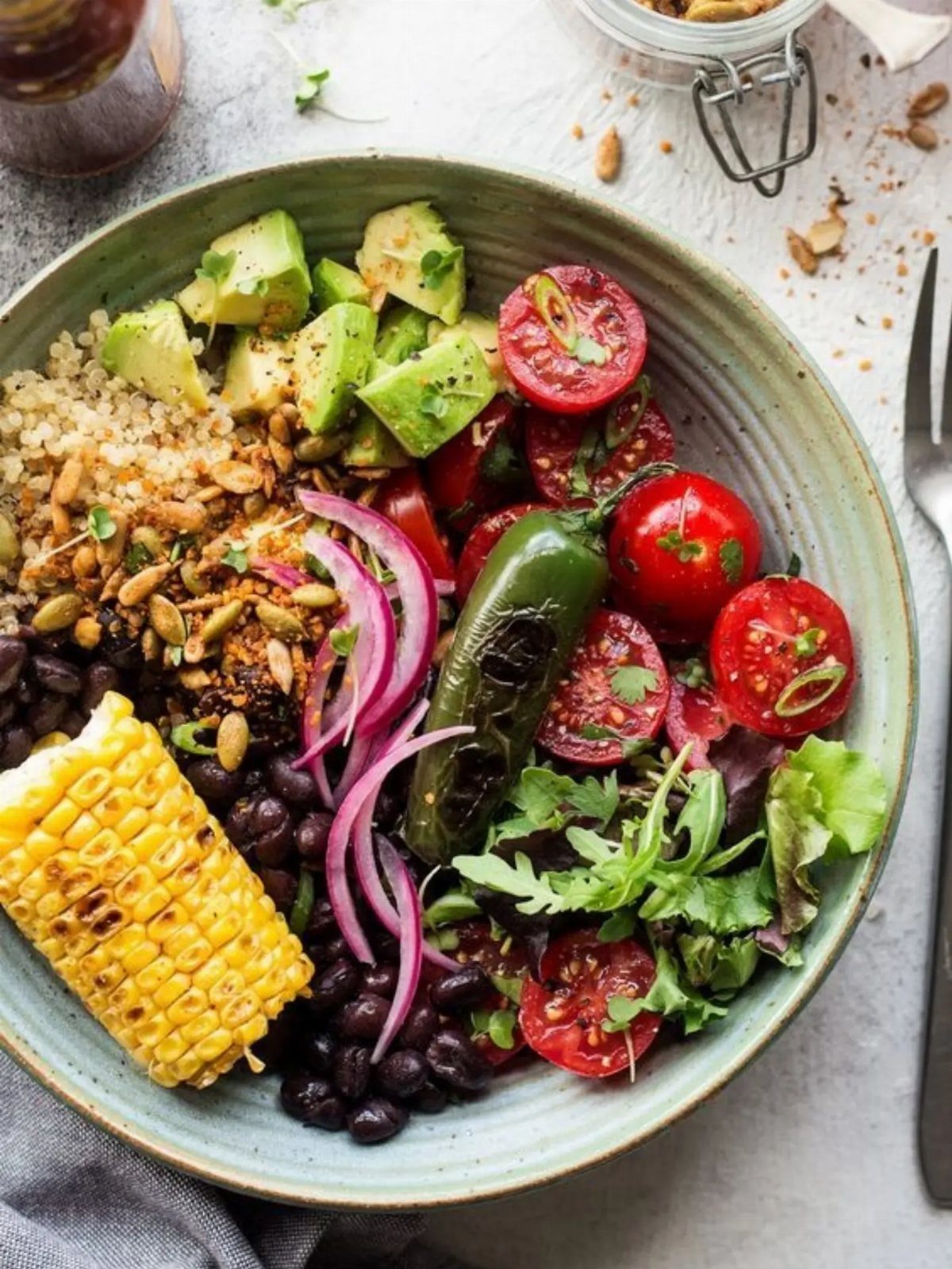 Nutritious bowl with quinoa, black beans, corn, avocado, and fresh vegetables