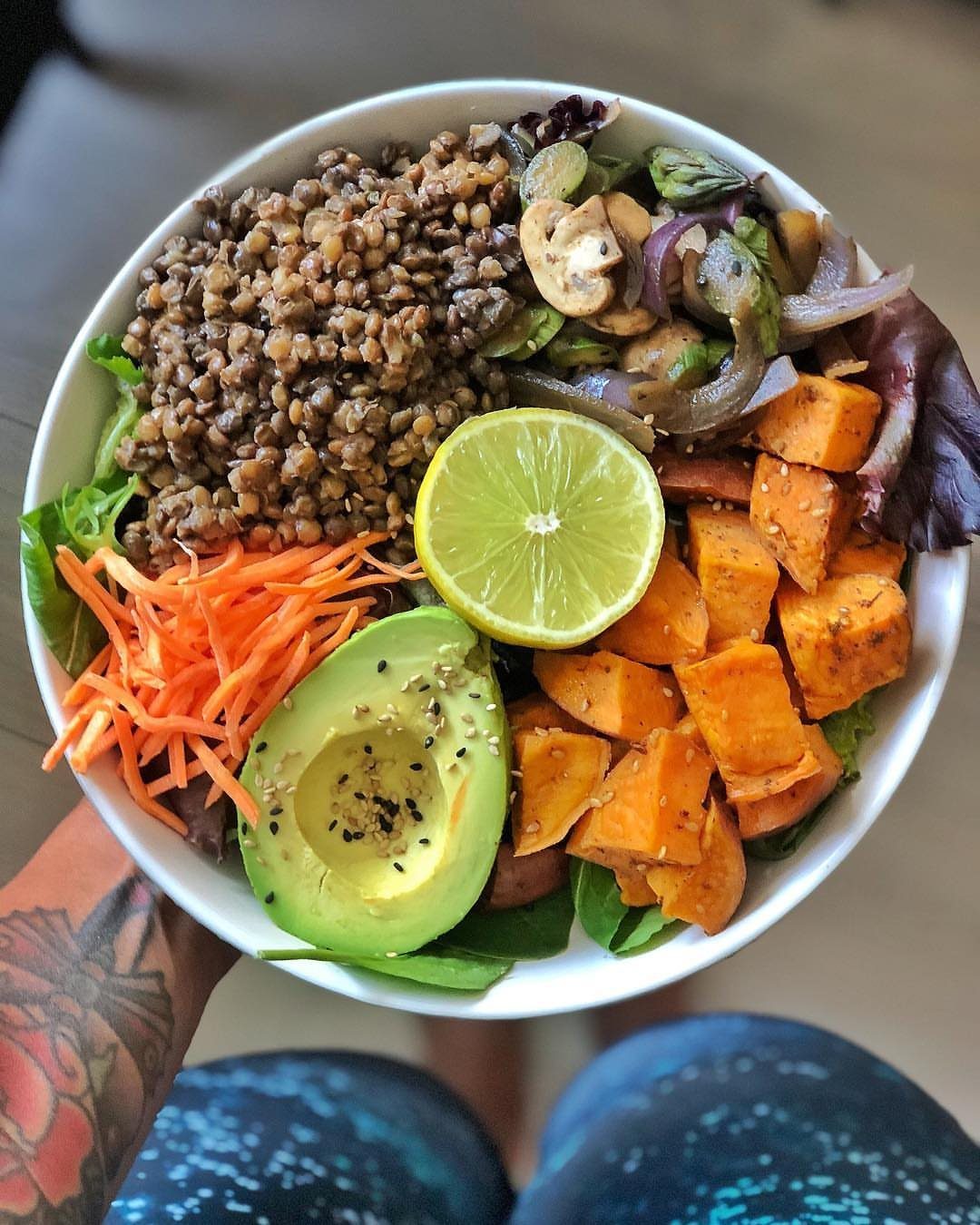 Bowl of lentils, sweet potatoes, avocado, and carrots on a bed of greens.