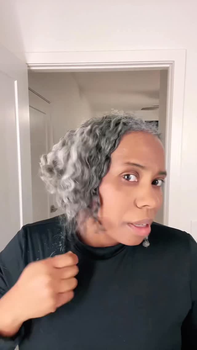 Woman with curly silver and gray hair wearing a black turtleneck shirt.