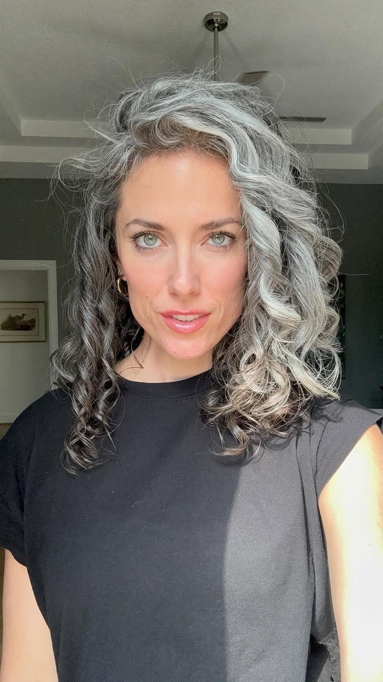 Woman with curly salt and pepper gray hair wearing a black t-shirt.