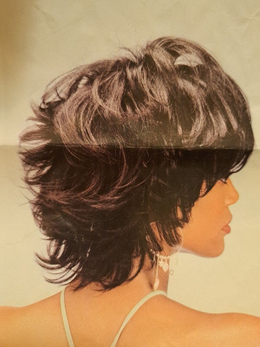 Dark brown grown out pixie cut with significant volume at the crown.