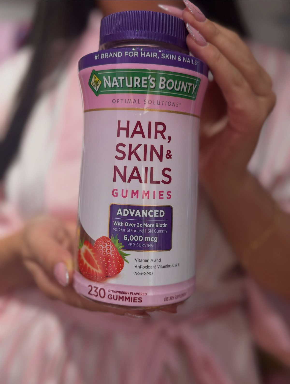 Nature's Bounty Hair, Skin & Nails Gummies bottle held by a person