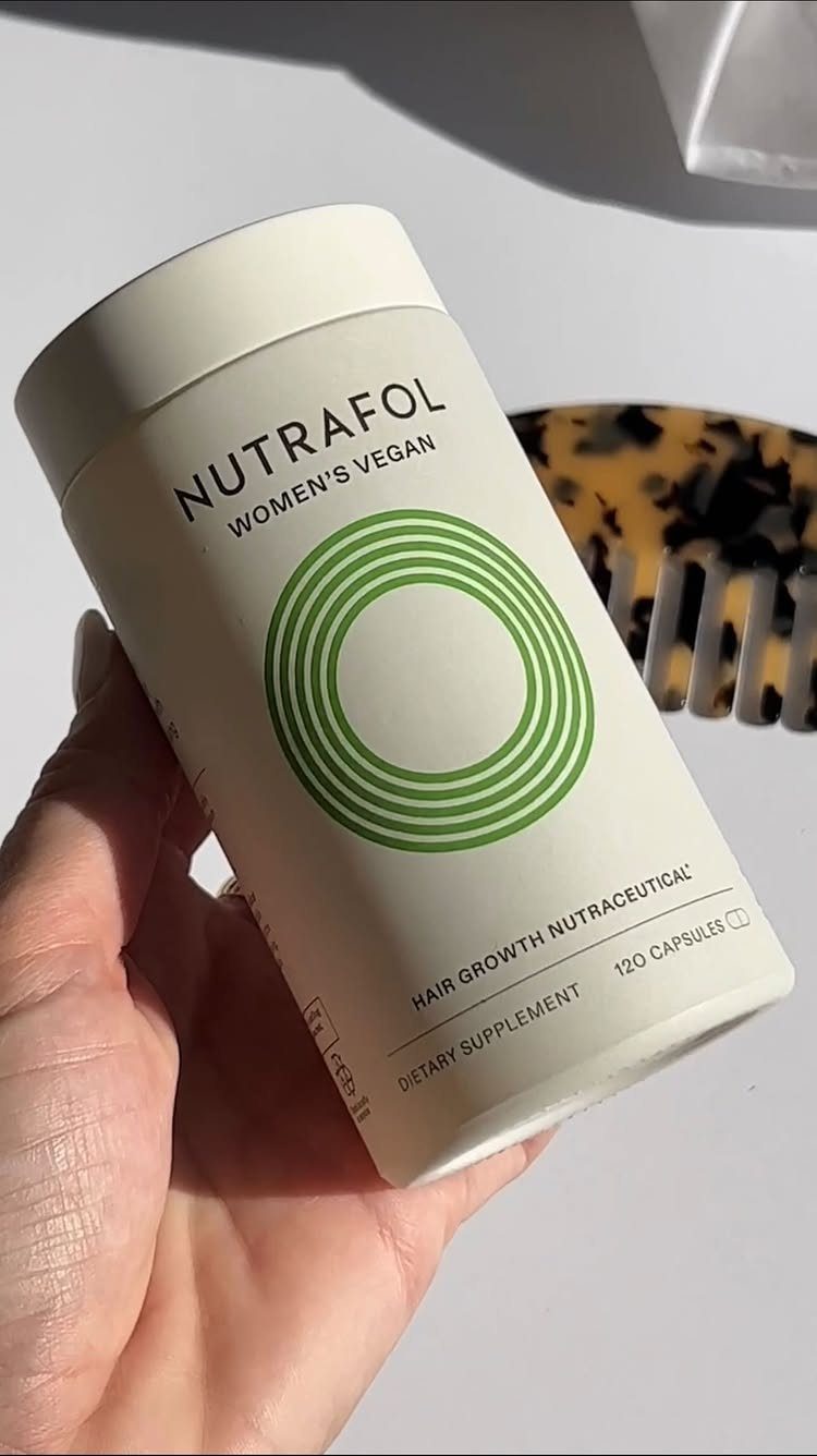 Nutrafol Women's Vegan hair growth supplement bottle held in a hand.