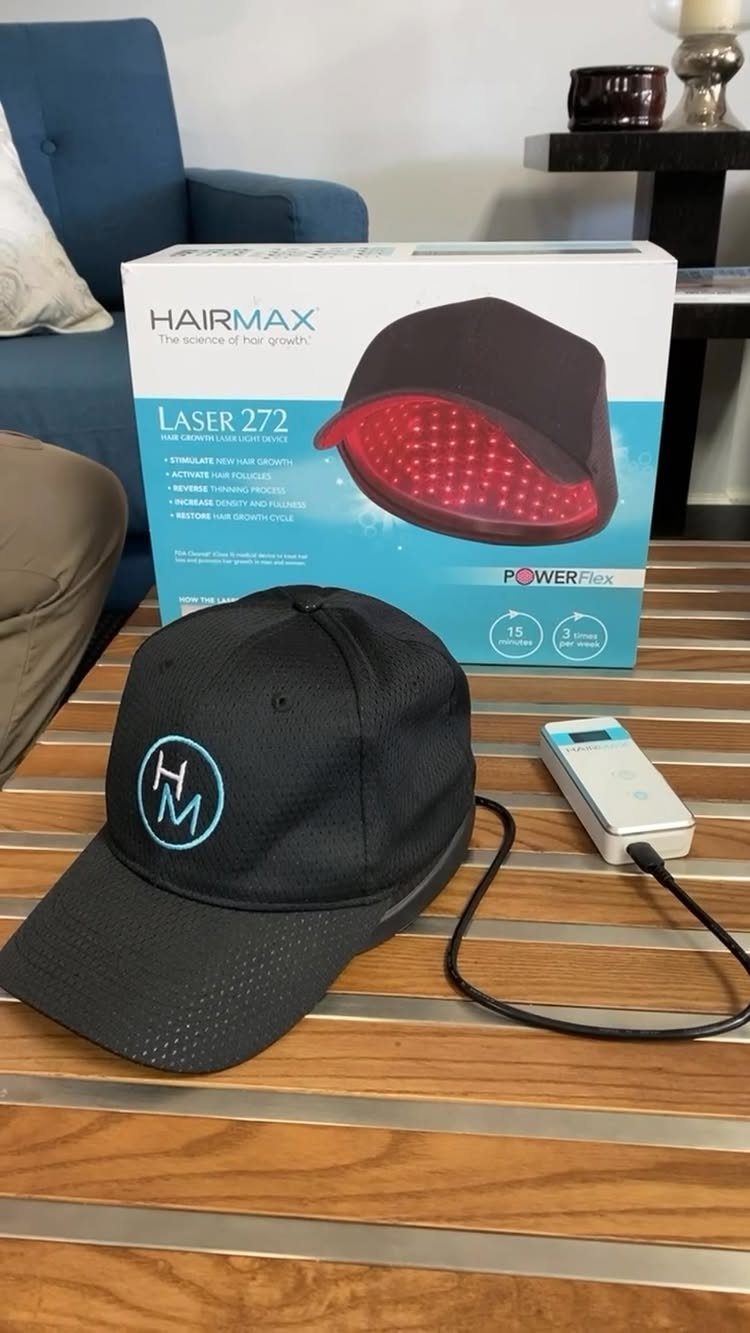 Laser therapy cap and power device next to its product packaging on a table.