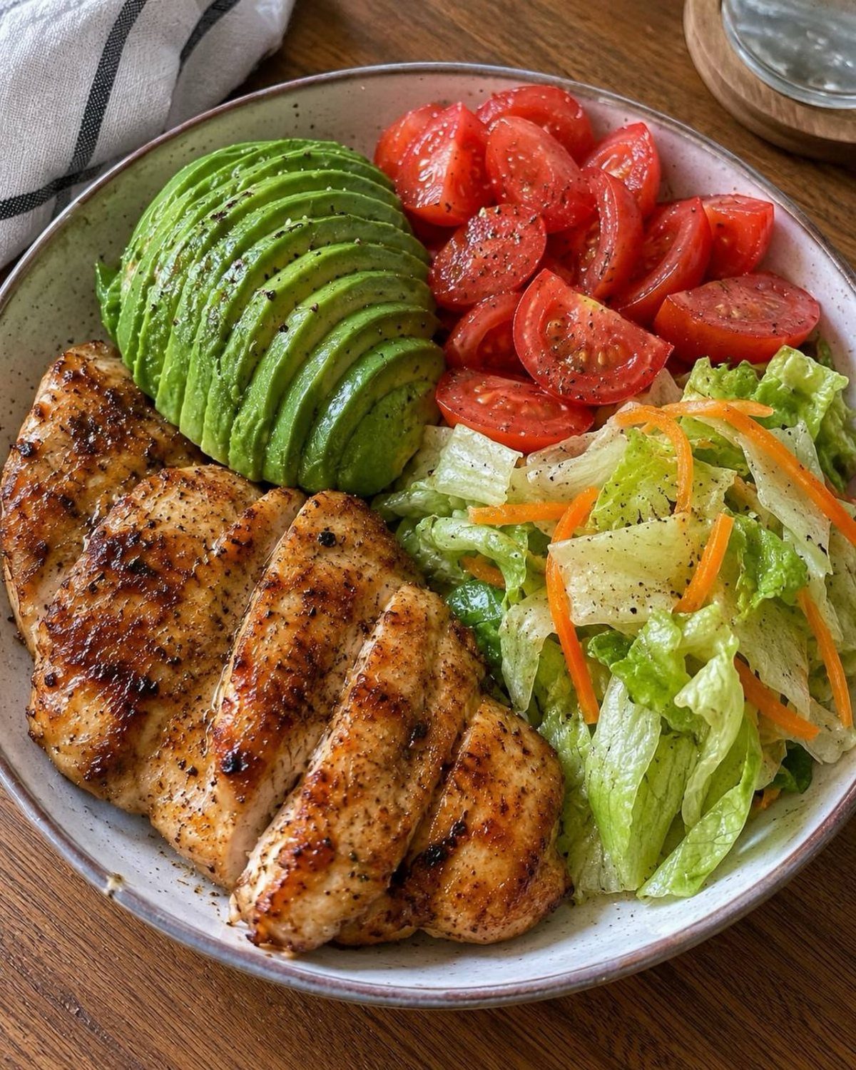 Grilled chicken breast with sliced avocado, cherry tomatoes, and a fresh garden salad.