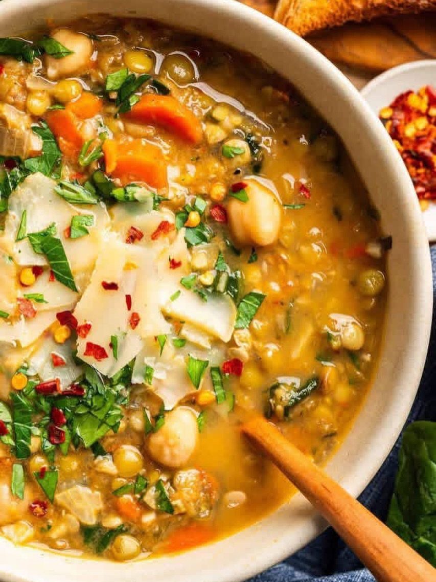 Vegetable lentil soup with chickpeas and parmesan cheese in a white bowl