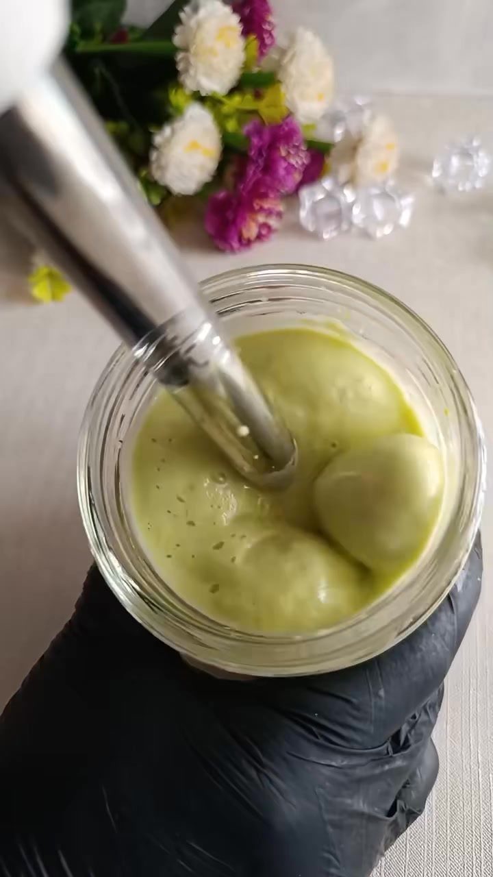 Green avocado hair mask being blended in a glass jar with an immersion blender