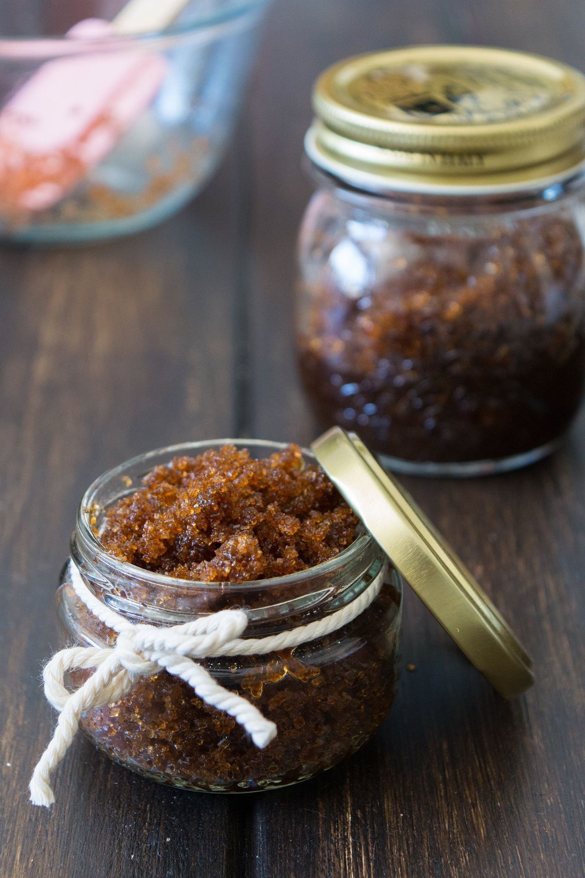 Brown sugar scrub in glass jars with a white string and gold lids.