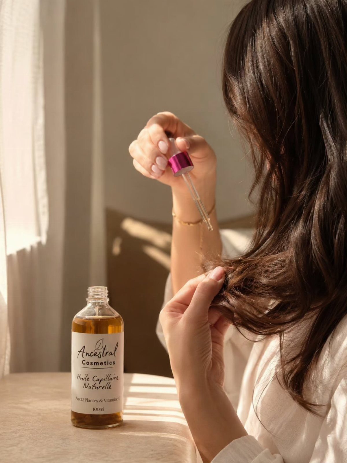 Woman applying hair oil from a dropper to her long brown wavy hair