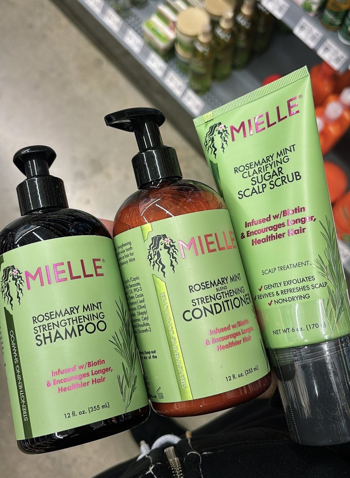 Mielle Rosemary Mint shampoo, conditioner, and scalp scrub products on a store shelf.