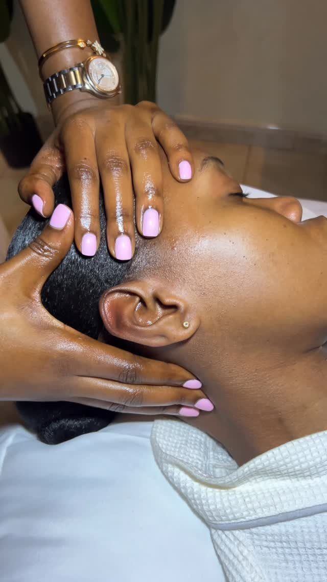 Hands massaging the scalp and forehead of a person lying down during a treatment.