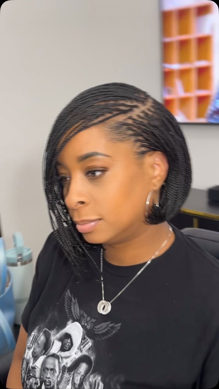 Woman with a chin-length braided bob hairstyle and a black graphic t-shirt.