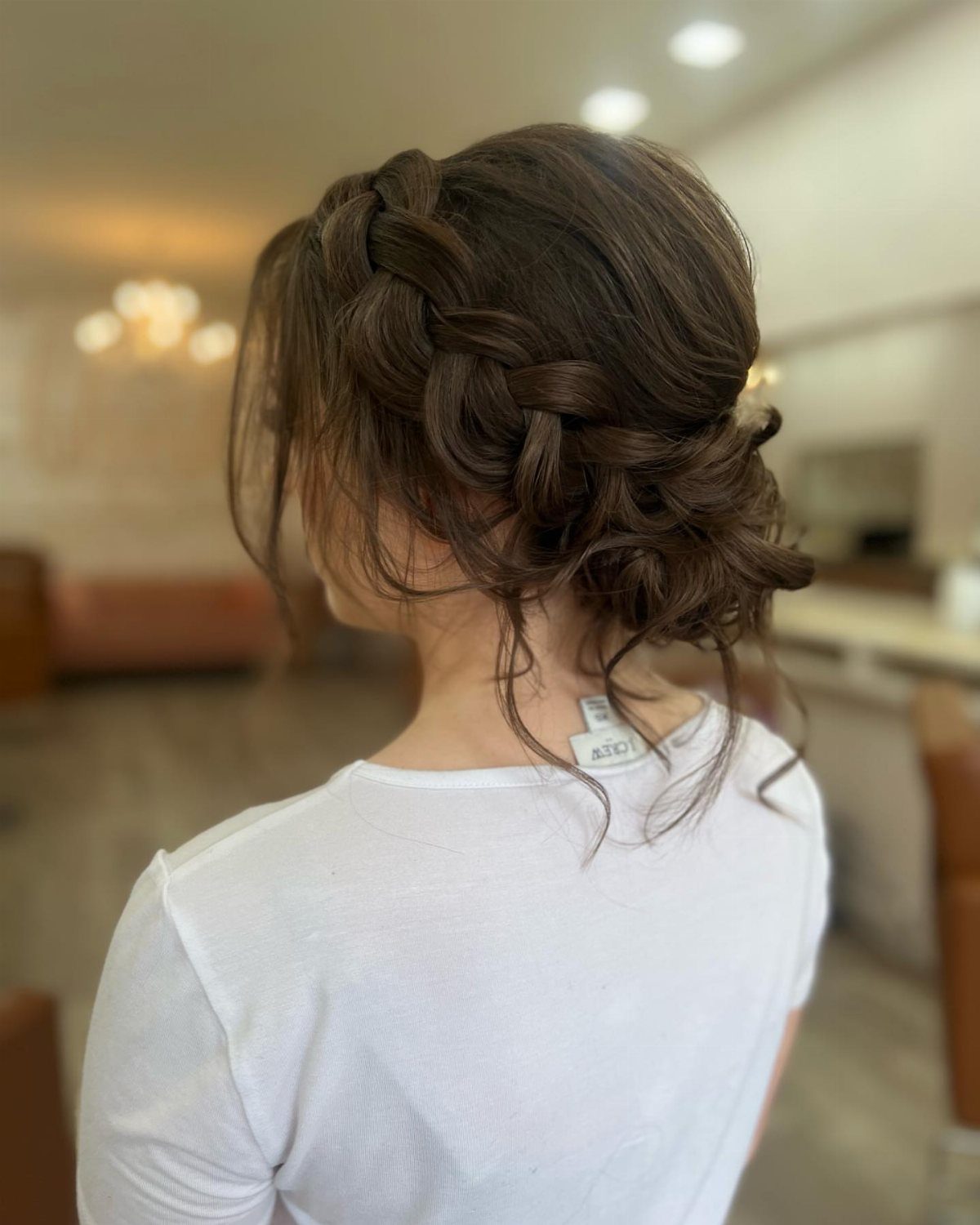 Brown hair styled in a side braid gathered into a low textured bun.