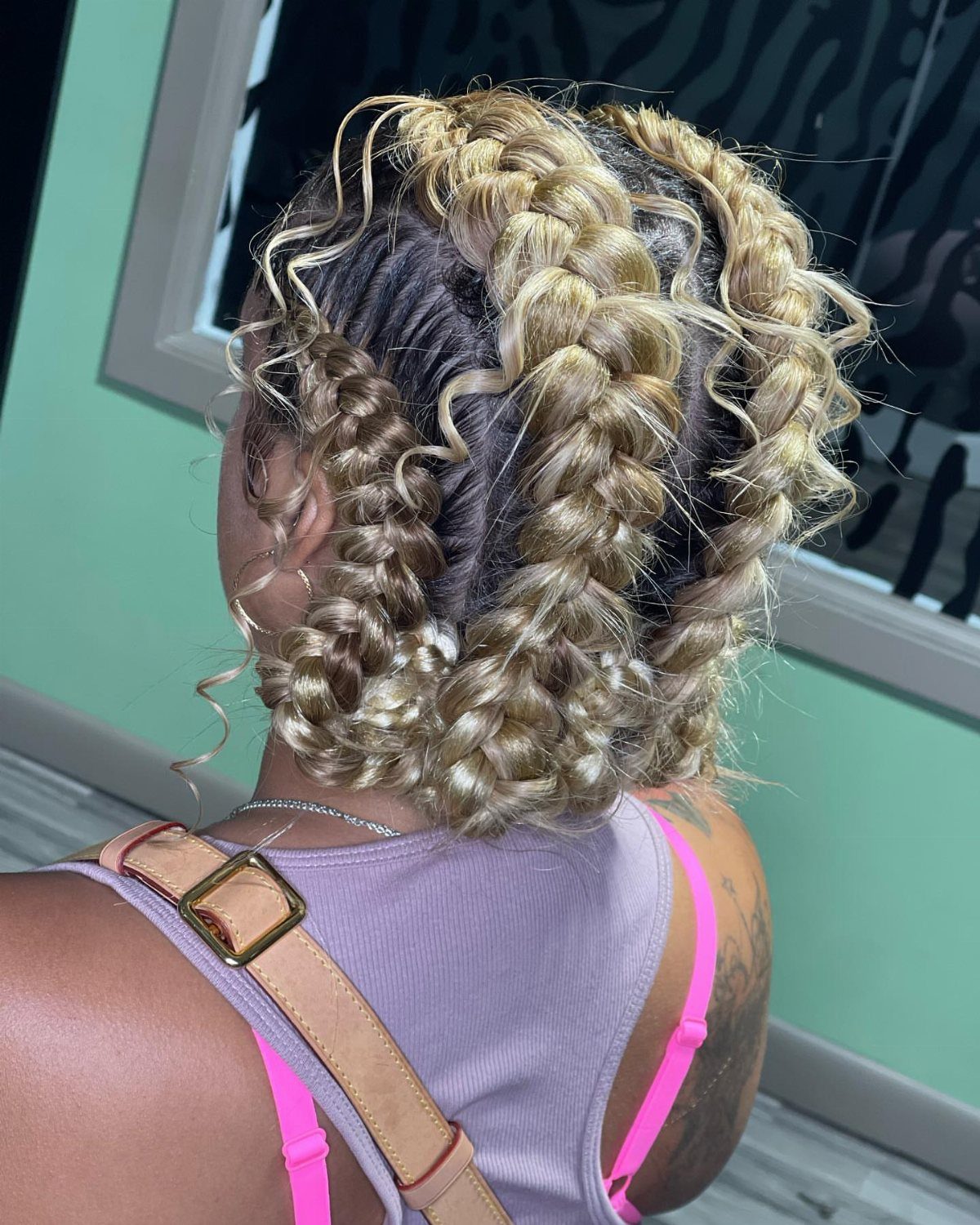 Blonde and brown goddess braids styled in whimsical, looping patterns across the scalp.