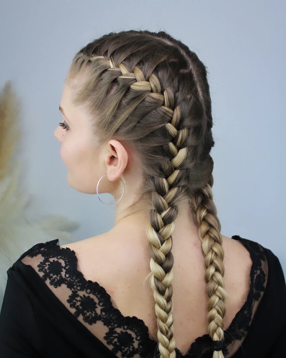 Woman with blonde hair styled in two thick Dutch braids hanging down her back.