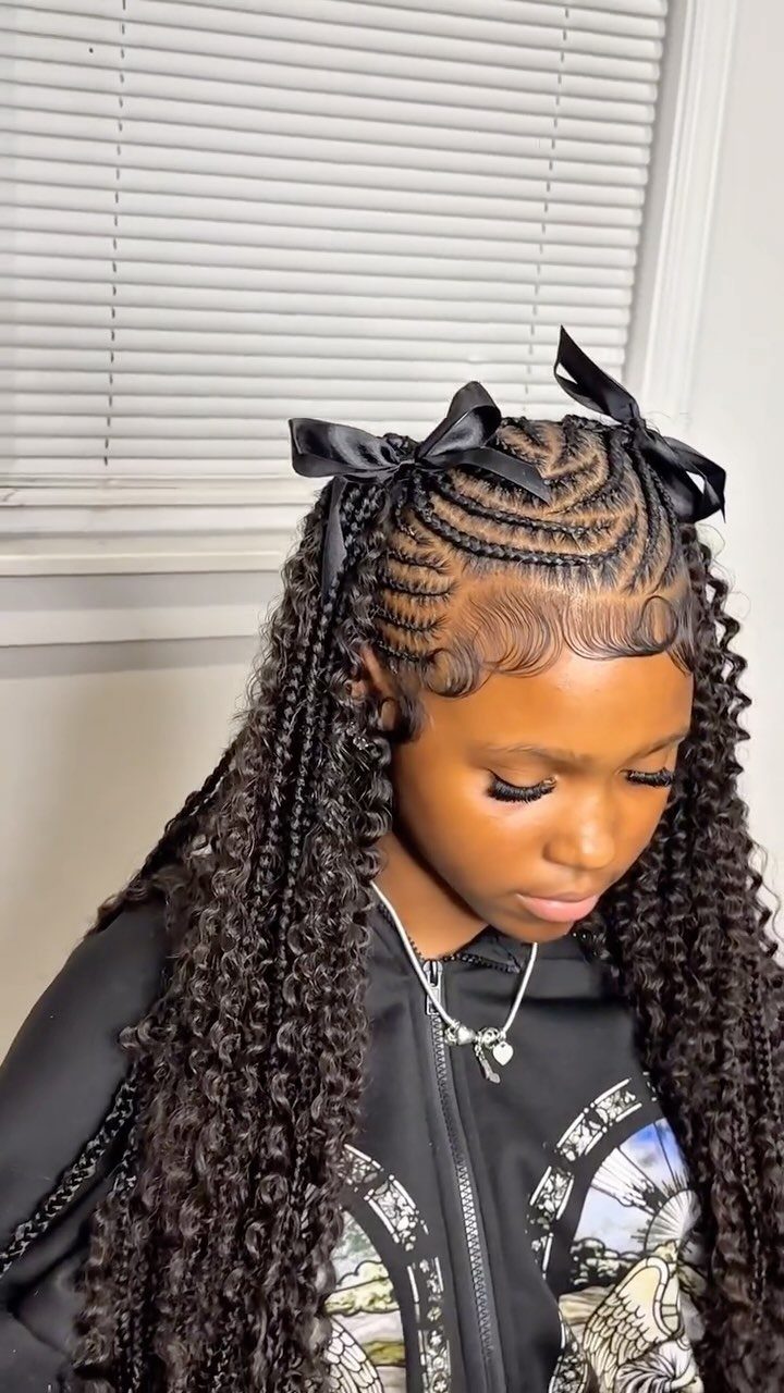 Young girl with half-up scalp braids tied with black bows and loose curly braids.