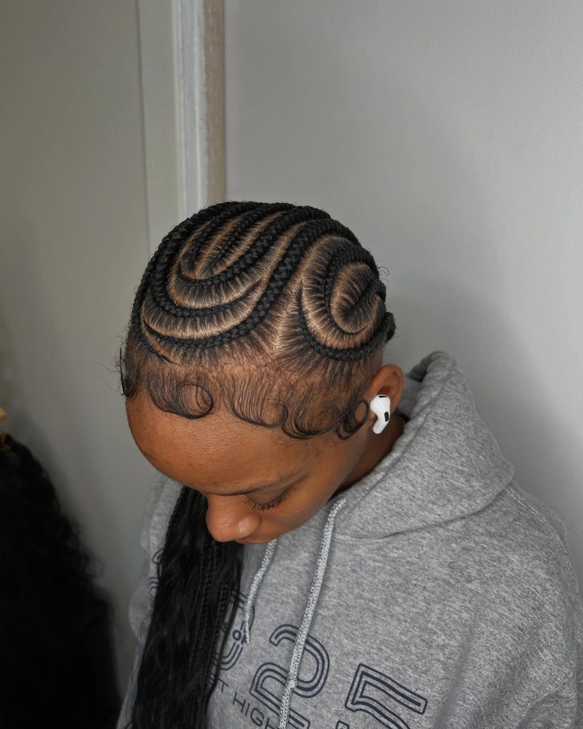 Person with jumbo scalp braids styled into a heart shape on the side.