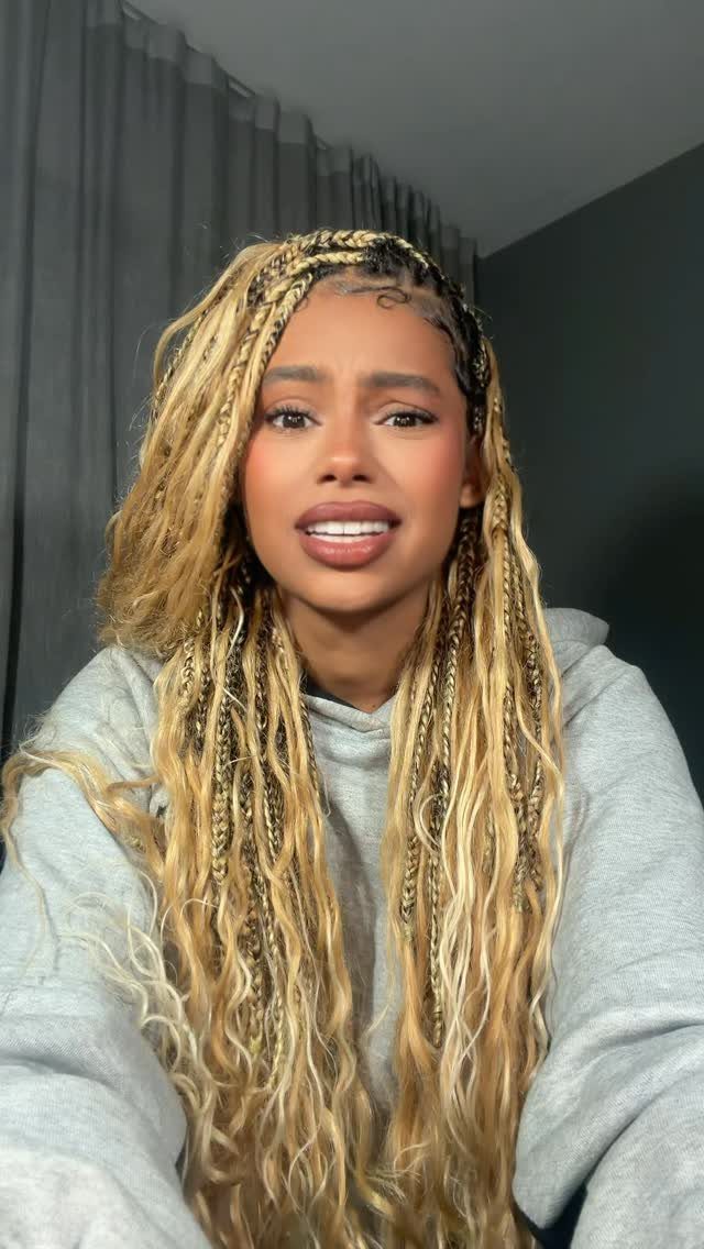Woman with long blonde and brown goddess box braids wearing a grey hoodie.