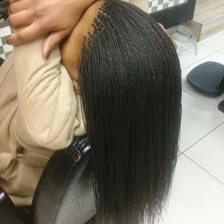 Micro braids on a person with dark hair in a salon setting.