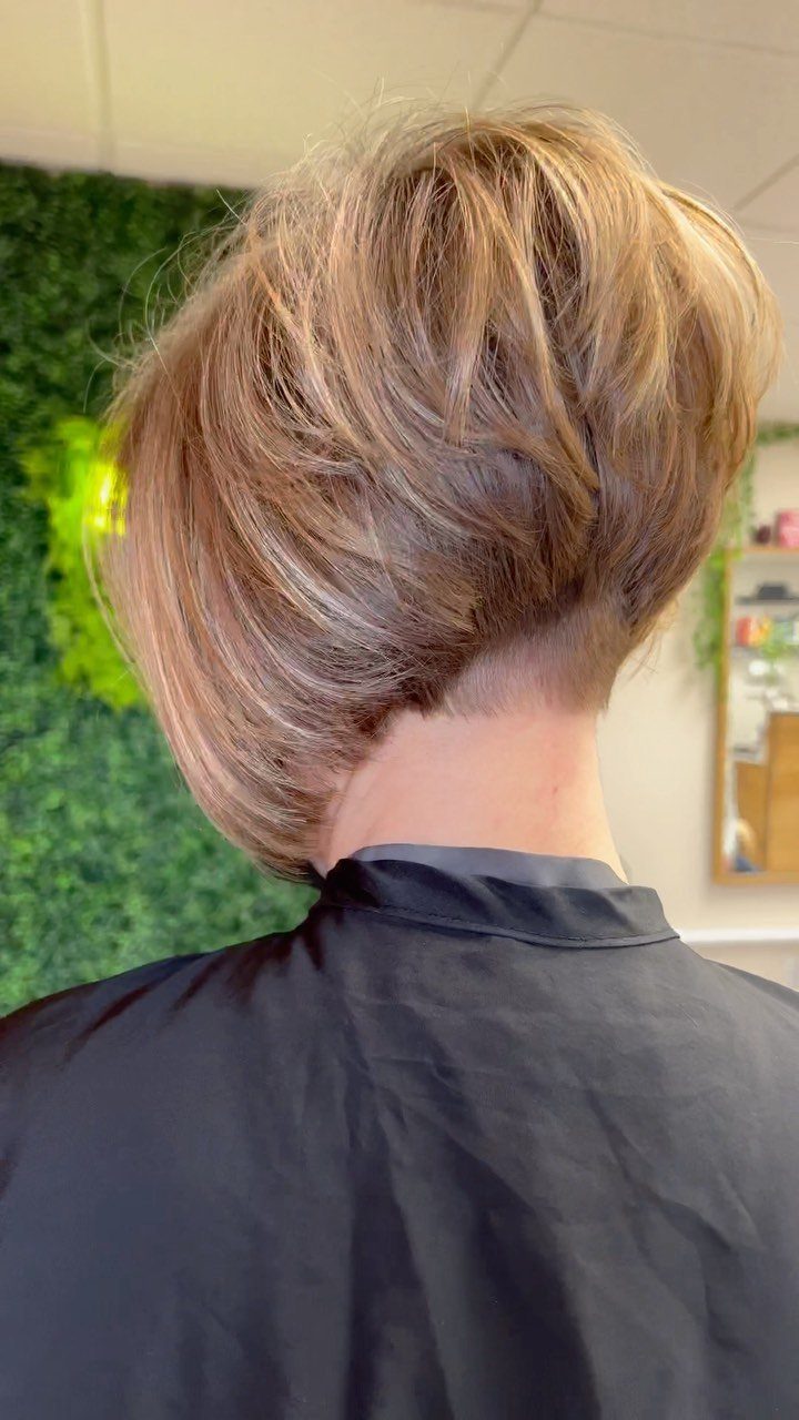 Short layered blonde haircut with a shaved undercut seen from the back.