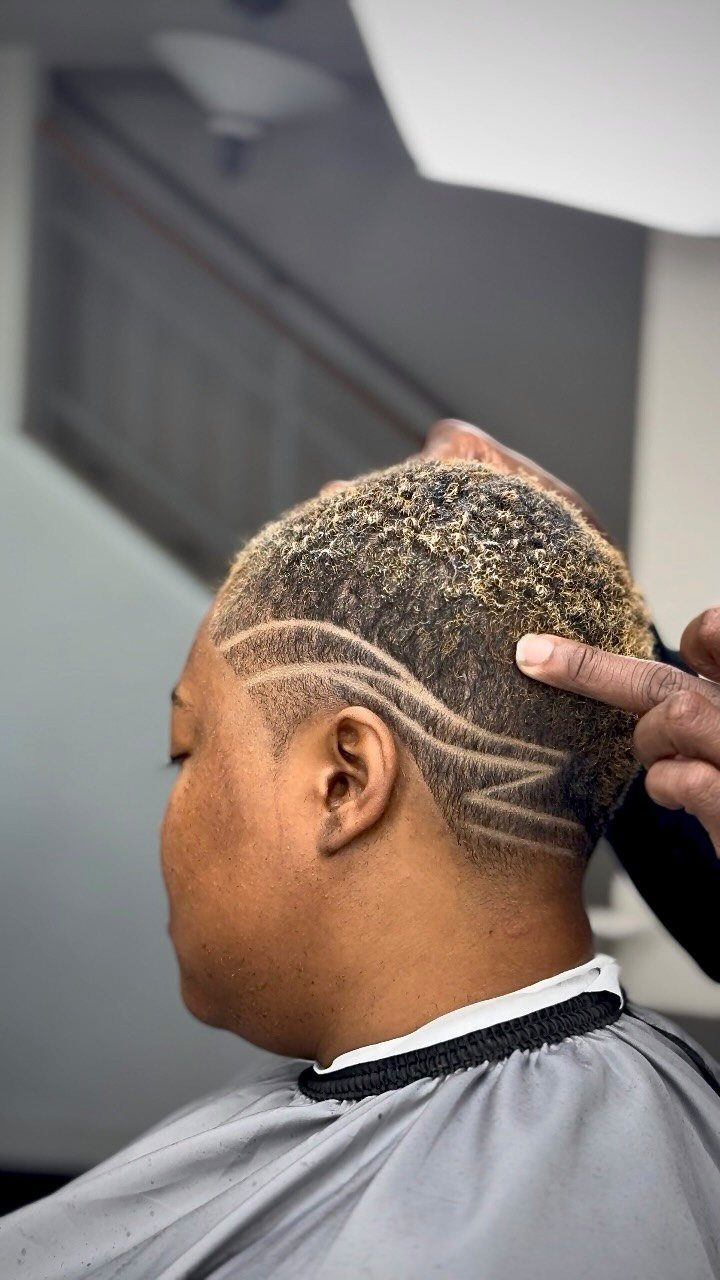 Person with short salt-and-pepper hair featuring shaved geometric patterns on the side.