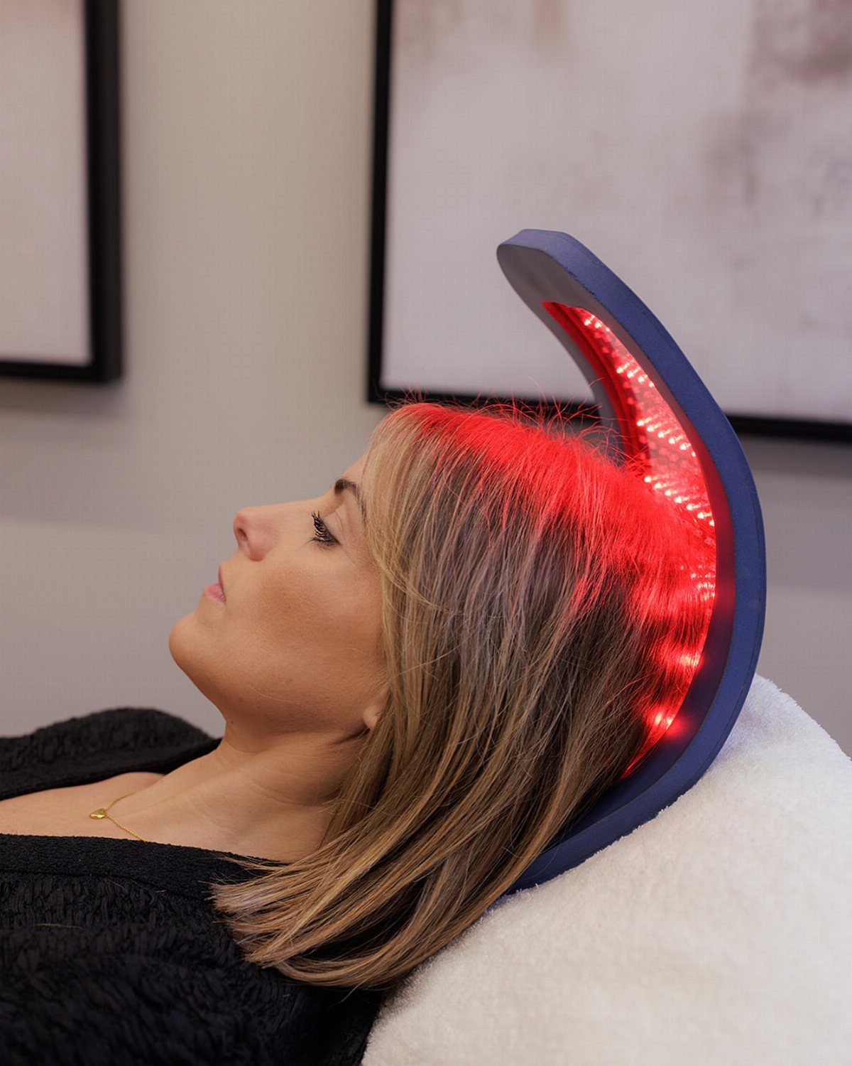 Woman using a red light therapy helmet for hair growth on her scalp