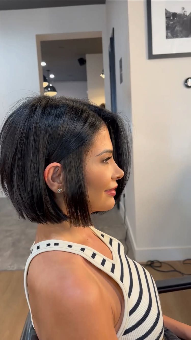 Woman with a dark, chin-length blunt bob haircut wearing a striped top.