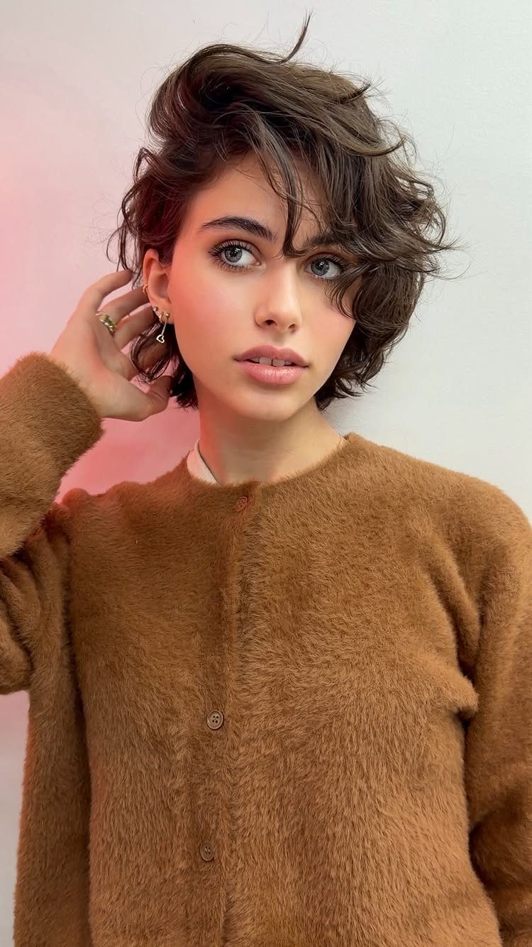 Woman with a short, layered brown bixie haircut wearing a fuzzy brown cardigan.
