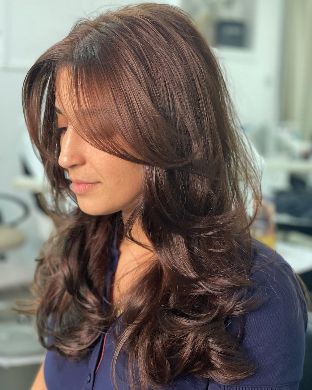 Woman with long brown hair styled in a voluminous butterfly cut with layers.