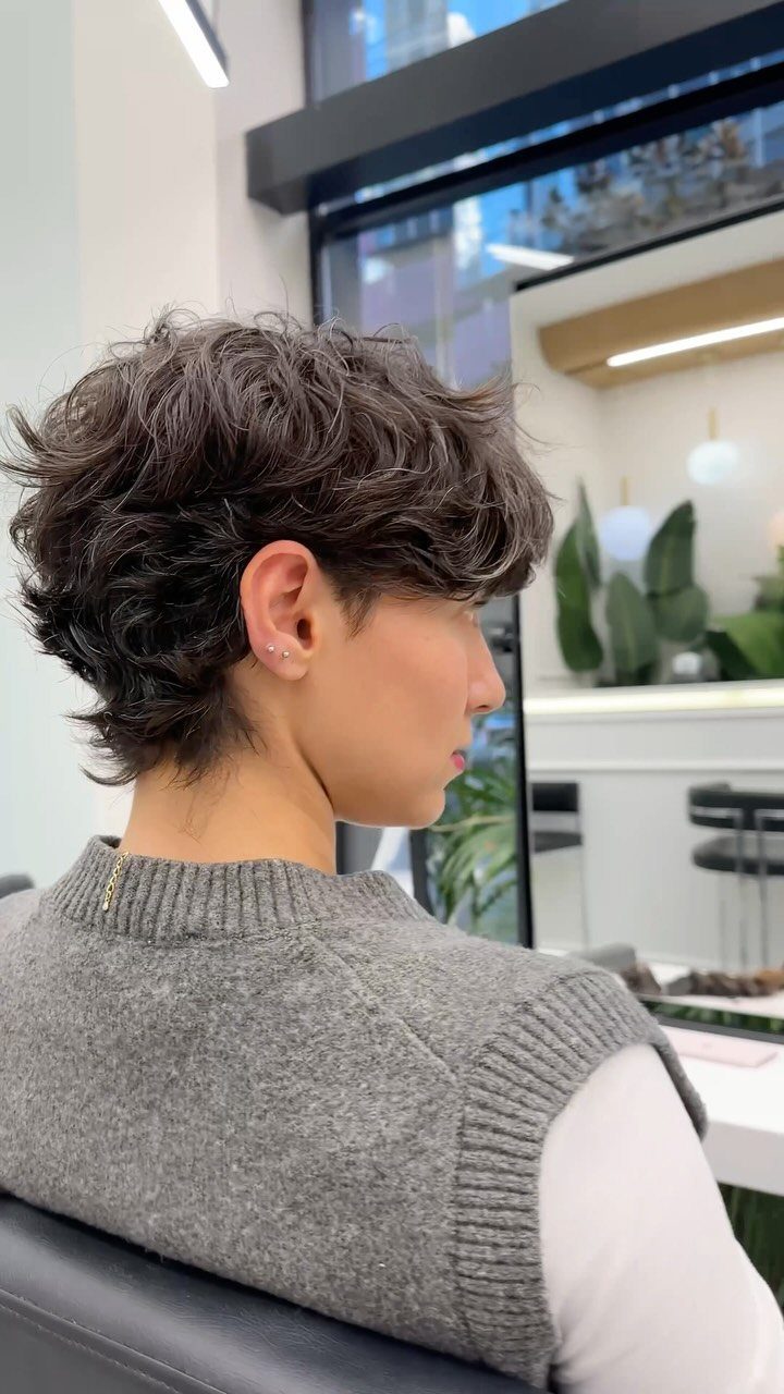 Person with a short, wavy brown pixie cut seen from a side profile.