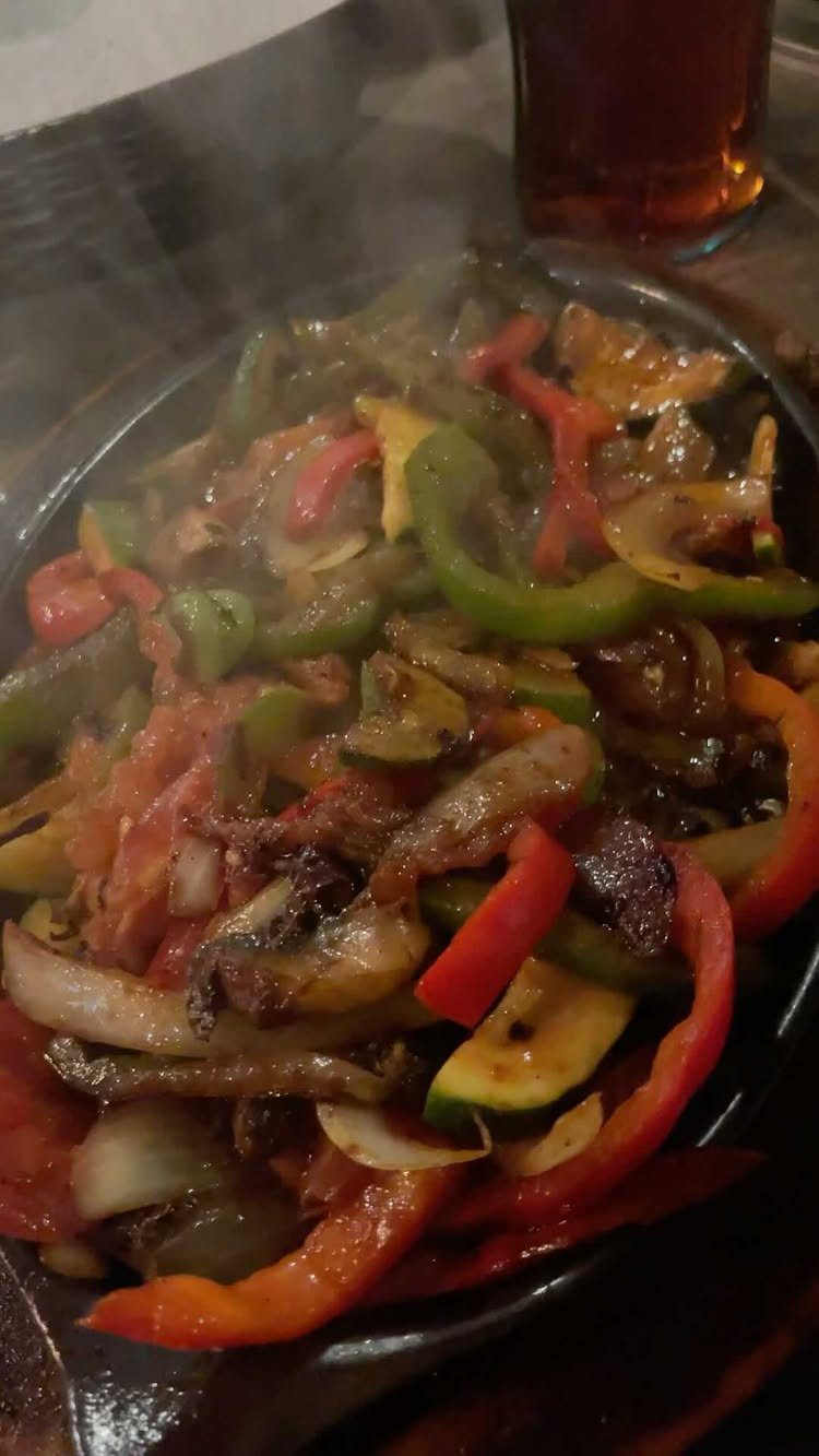 Sautéed red and green bell peppers with onions and zucchini in a skillet.